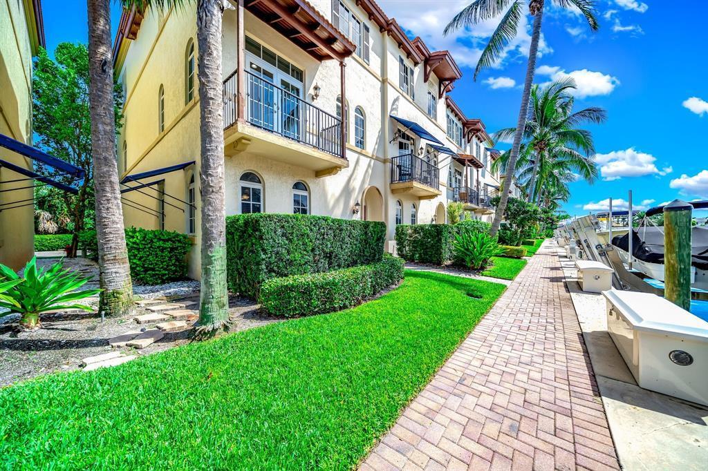 A multi-story waterfront townhouse with balconies, manicured hedges, and a brick walkway beside a canal — 824 Virginia Garden Drive, Boynton Beach FL 33435, BOYNTON BEACH, FL