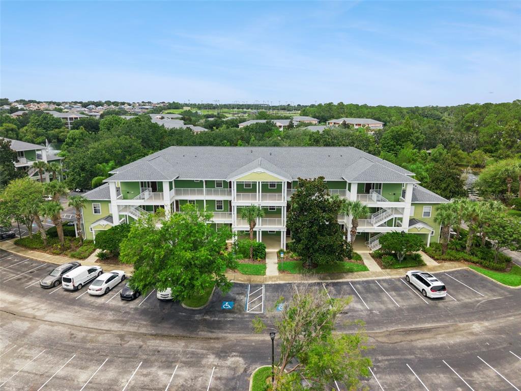 An aerial view shows a three-story green apartment building with a parking lot in front — 110 WATLING WAY, DAVENPORT, FL