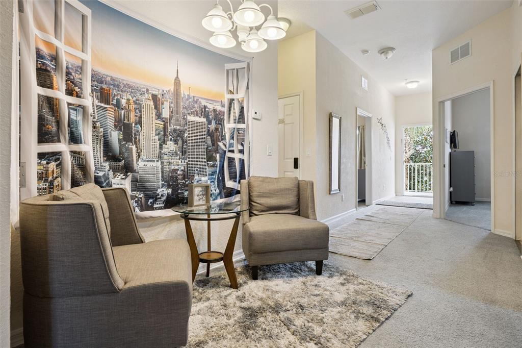 A seating area features two gray armchairs, a glass-topped table, and a large city mural — 110 WATLING WAY, DAVENPORT, FL