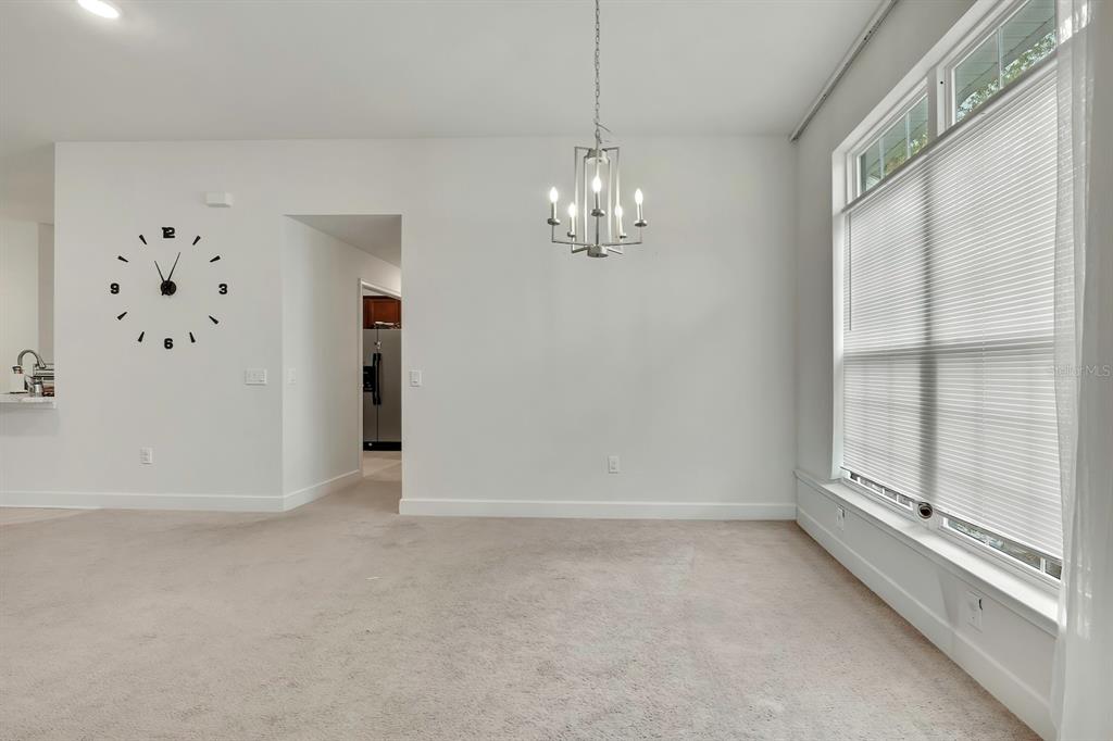A dining area features a modern chandelier, a wall clock, and large windows with blinds — 10358 MUSA ROAD, SPRING HILL, FL