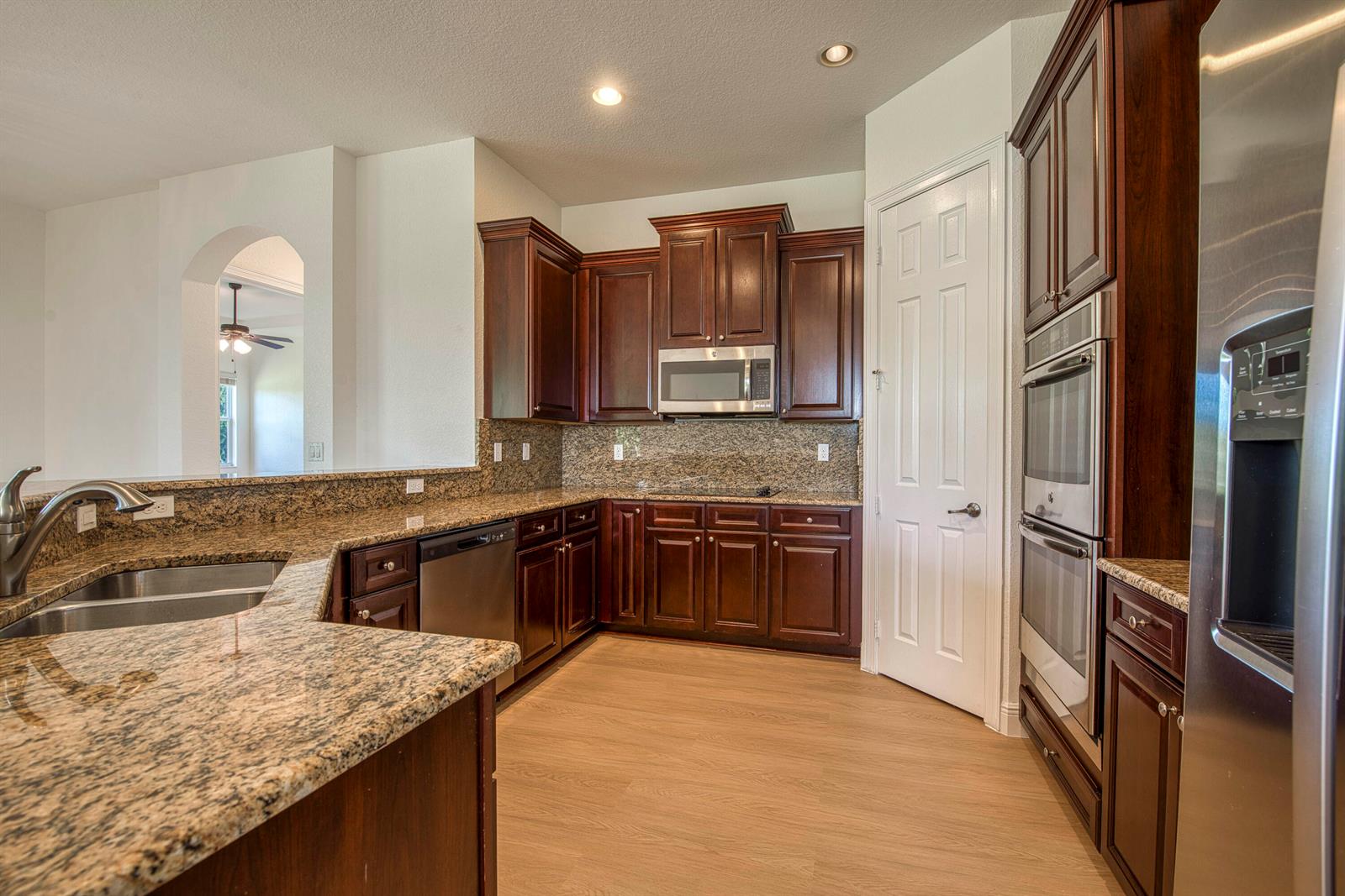 A kitchen features dark wood cabinets, granite countertops, stainless steel appliances, and light wood flooring — 172 Manor Circle, Jupiter FL 33458, JUPITER, FL