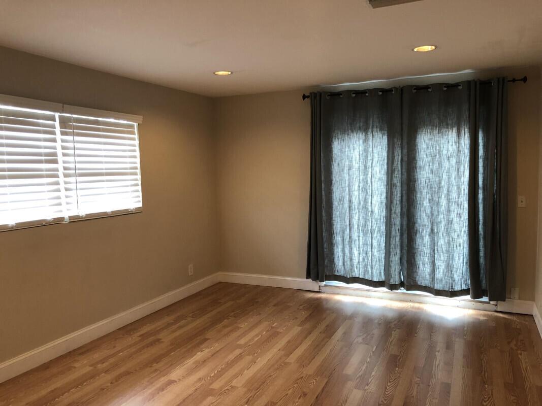 An empty room with hardwood floors, a window with blinds, and sliding glass patio doors — 279 SE 8th Terrace # A, Deerfield Beach FL 33441, DEERFIELD BEACH, FL