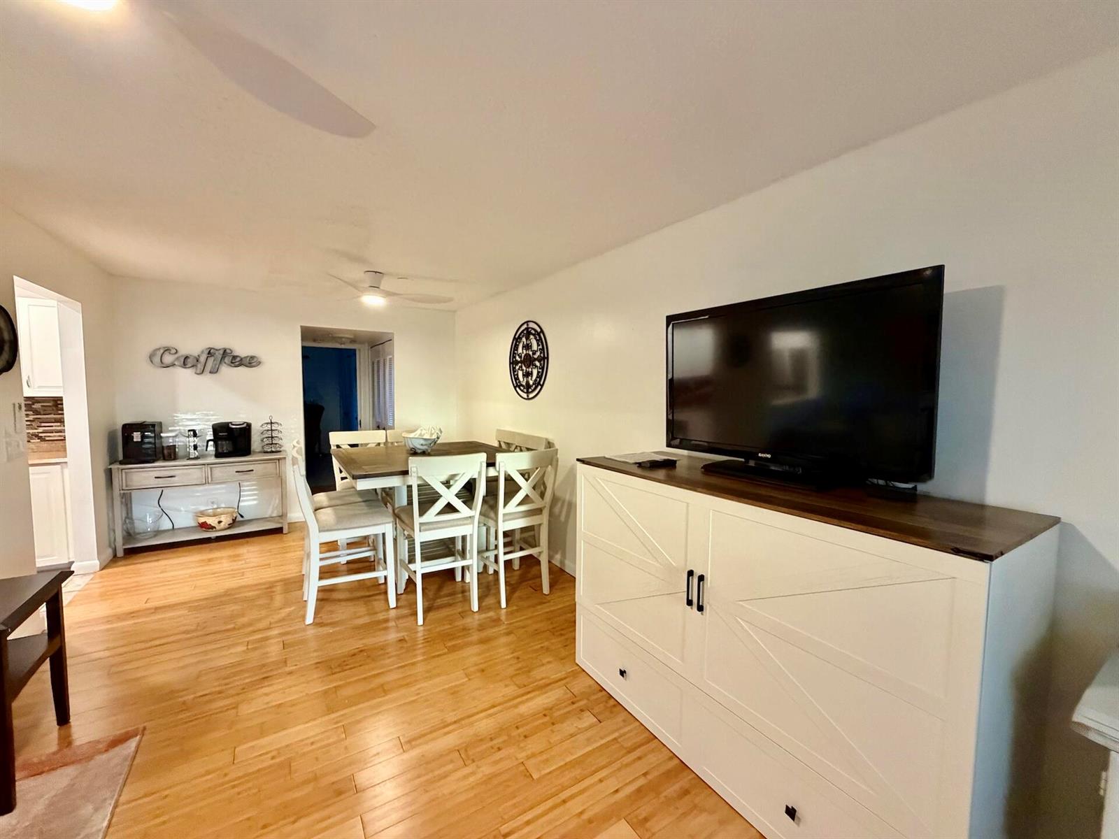 A living and dining area features hardwood floors, a white media console, and a dining set — 335 Durham Circle # J, Deerfield Beach FL 33442, DEERFIELD BEACH, FL