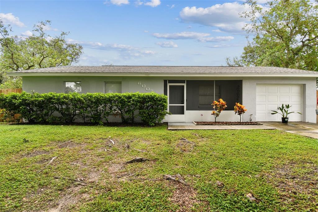 A single-story house with a gray exterior, a front hedge, and an attached one-car garage — 6007 CALENDAR COURT W, LAKELAND, FL