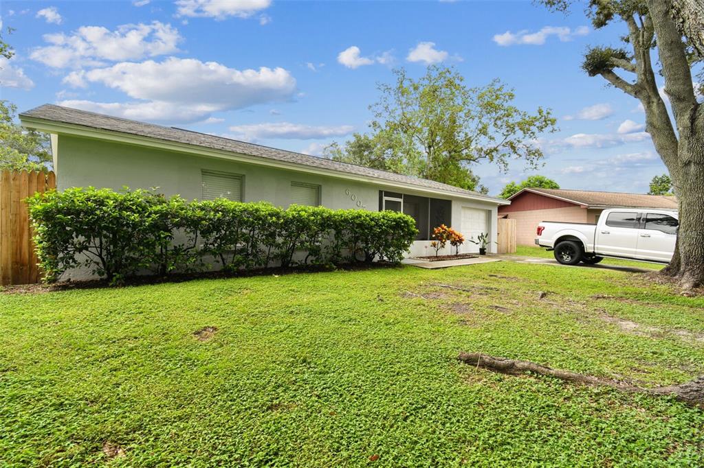 A single-story house with a light-colored exterior, a hedge, and a white pickup truck parked nearby — 6007 CALENDAR COURT W, LAKELAND, FL