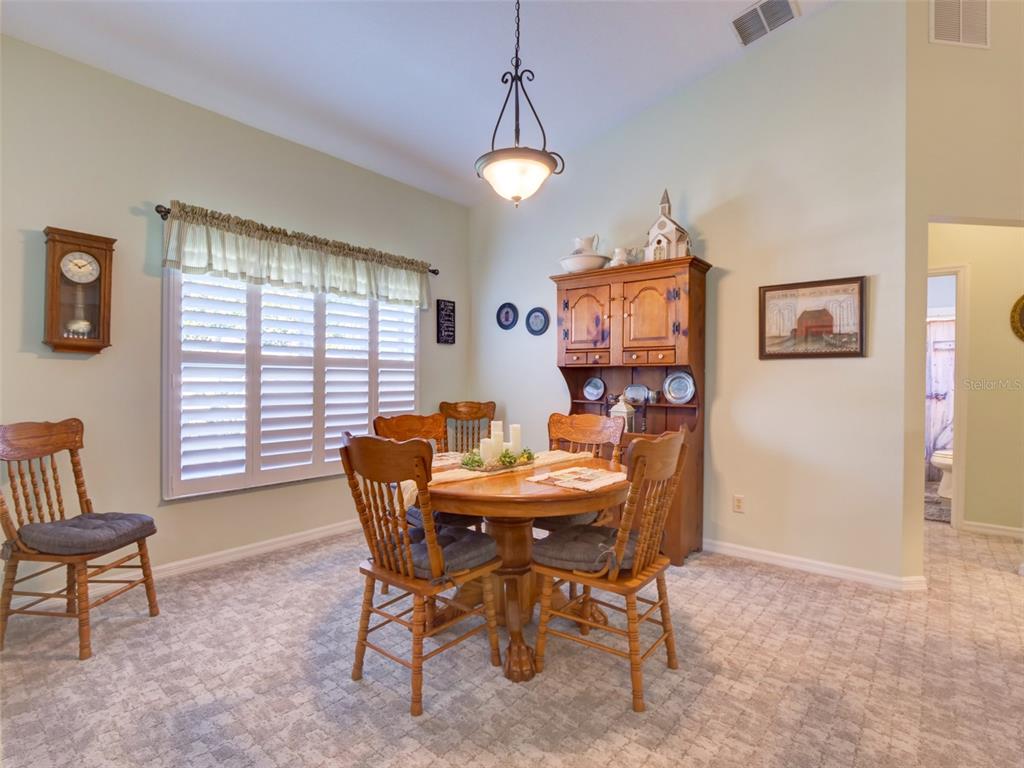 A dining room features a wooden table and chairs, a hutch, and carpeted flooring — 3701 PLANTATION BOULEVARD, LEESBURG, FL