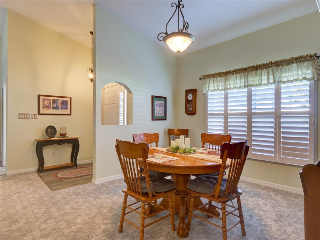 A dining room features a round wooden table, four chairs, and plantation shutters on windows — 3701 PLANTATION BOULEVARD, LEESBURG, FL