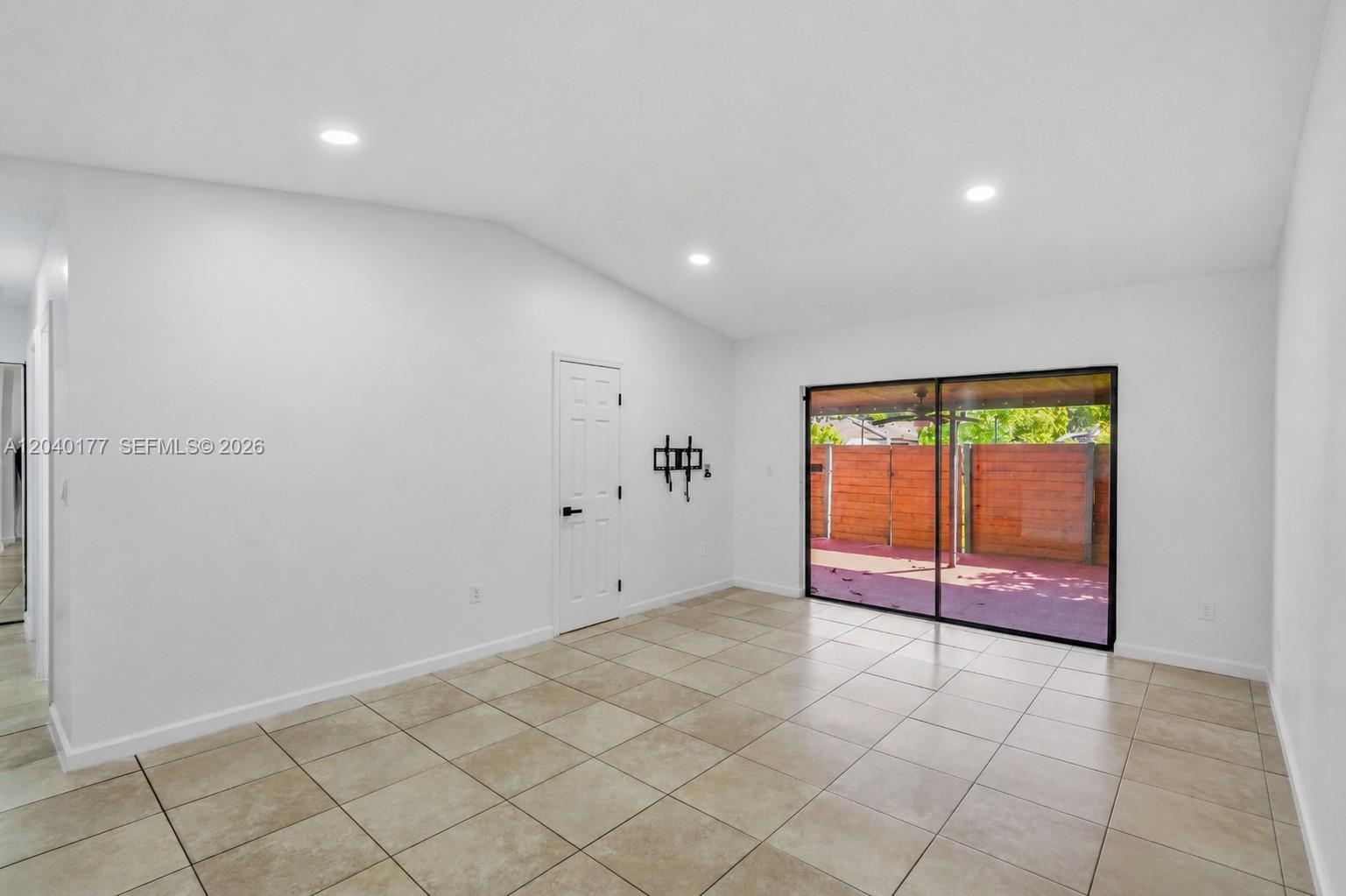 An empty room with white walls, tile flooring, recessed lighting, and a sliding glass door — 5113 SW 138th Ave Cir, Miami FL 33175, MIAMI, FL