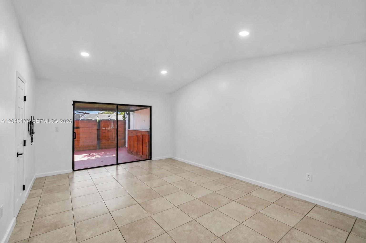 A bright room with white walls, tile flooring, recessed lighting, and sliding glass patio doors — 5113 SW 138th Ave Cir, Miami FL 33175, MIAMI, FL