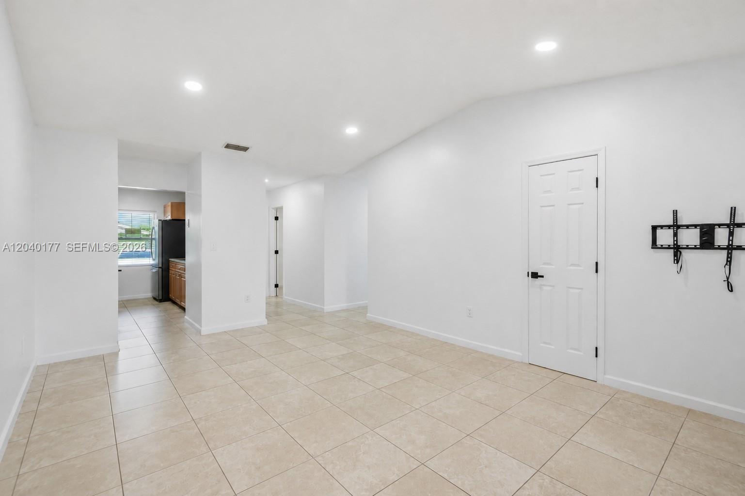 A bright, tiled living area features recessed lighting, a white door, and a wall-mounted TV bracket — 5113 SW 138th Ave Cir, Miami FL 33175, MIAMI, FL