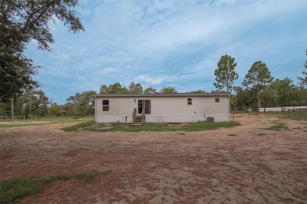 A single-story manufactured home sits on a sandy lot surrounded by trees — 8719 N PRESNELL TERRACE, DUNNELLON, FL
