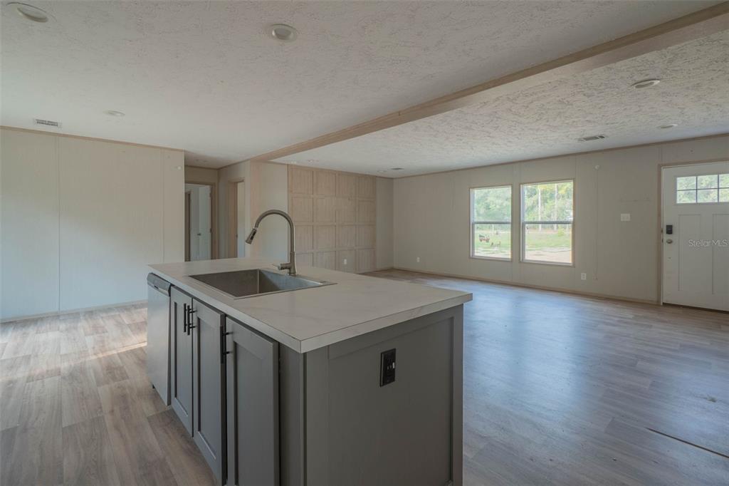 A kitchen island with a sink sits in an open-concept living area with light flooring — 8719 N PRESNELL TERRACE, DUNNELLON, FL