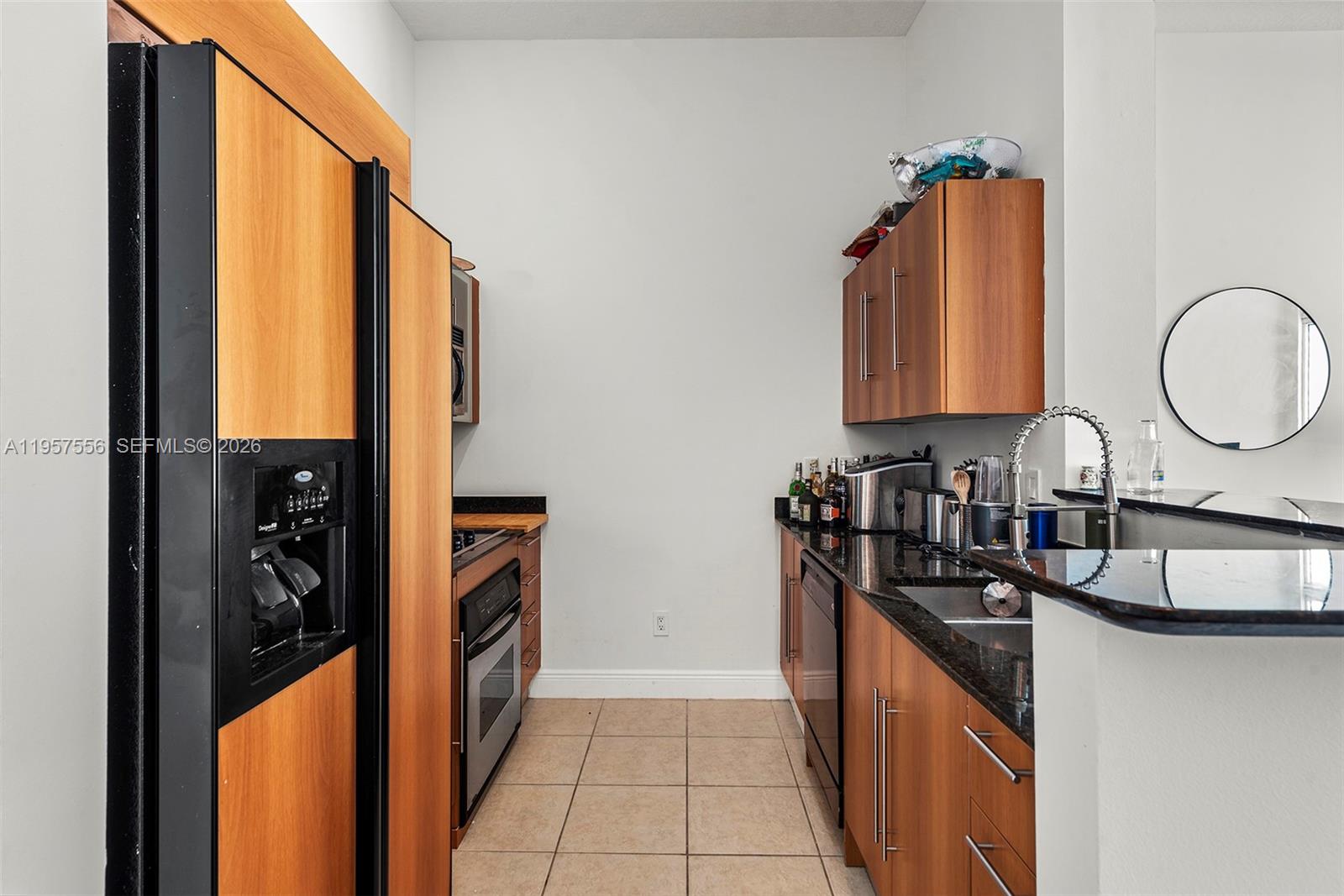 This galley kitchen features wood cabinetry, black granite countertops, and stainless steel appliances — 335 S Biscayne Blvd # 10, Miami FL 33131, MIAMI, FL