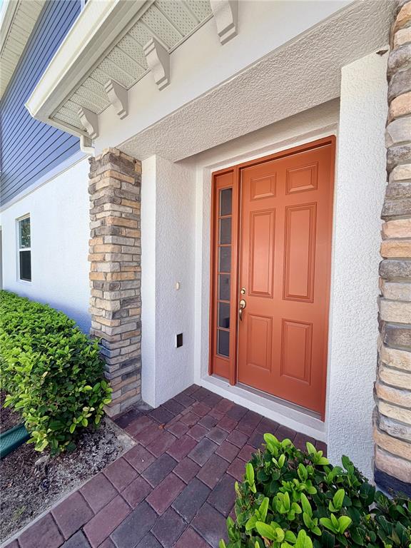 A front entrance with a red door, stone pillars, and a brick paver walkway — 4762 STERNWHEELER LANE, OVIEDO, FL