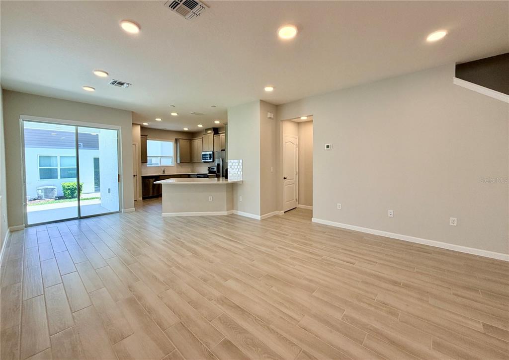 An open-concept living area features light wood-look tile flooring and a kitchen with a peninsula — 4762 STERNWHEELER LANE, OVIEDO, FL