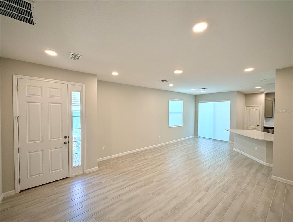 An open-concept living area features light-colored wood-look tile flooring, recessed lighting, and a kitchen island — 4762 STERNWHEELER LANE, OVIEDO, FL