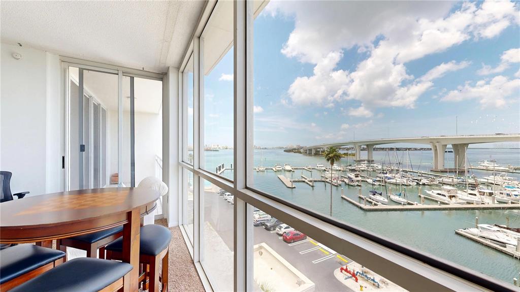 A sunroom with a dining table overlooks a marina and a large bridge — 100 PIERCE STREET UNIT 601, CLEARWATER, FL