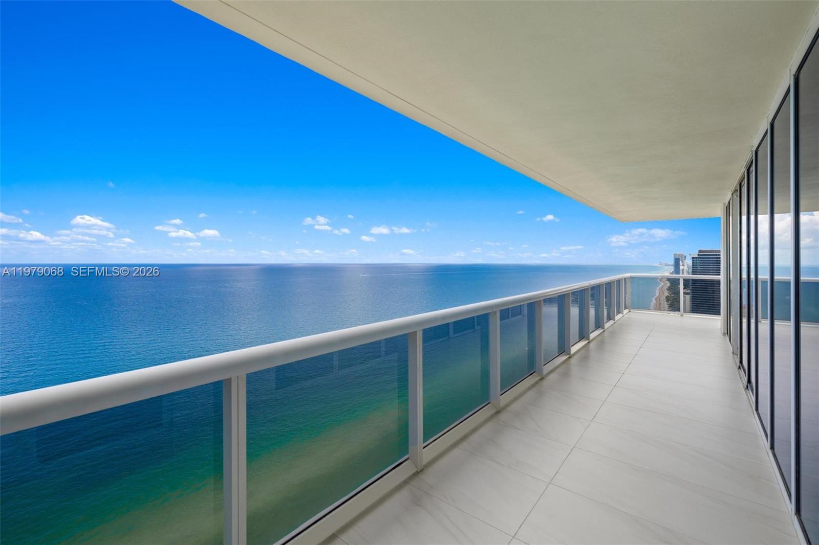 A high-rise balcony with a glass railing overlooks the ocean and a sandy beach — 1830 S Ocean Dr # 4502, Hallandale Beach FL 33009, HALLANDALE BEACH, FL
