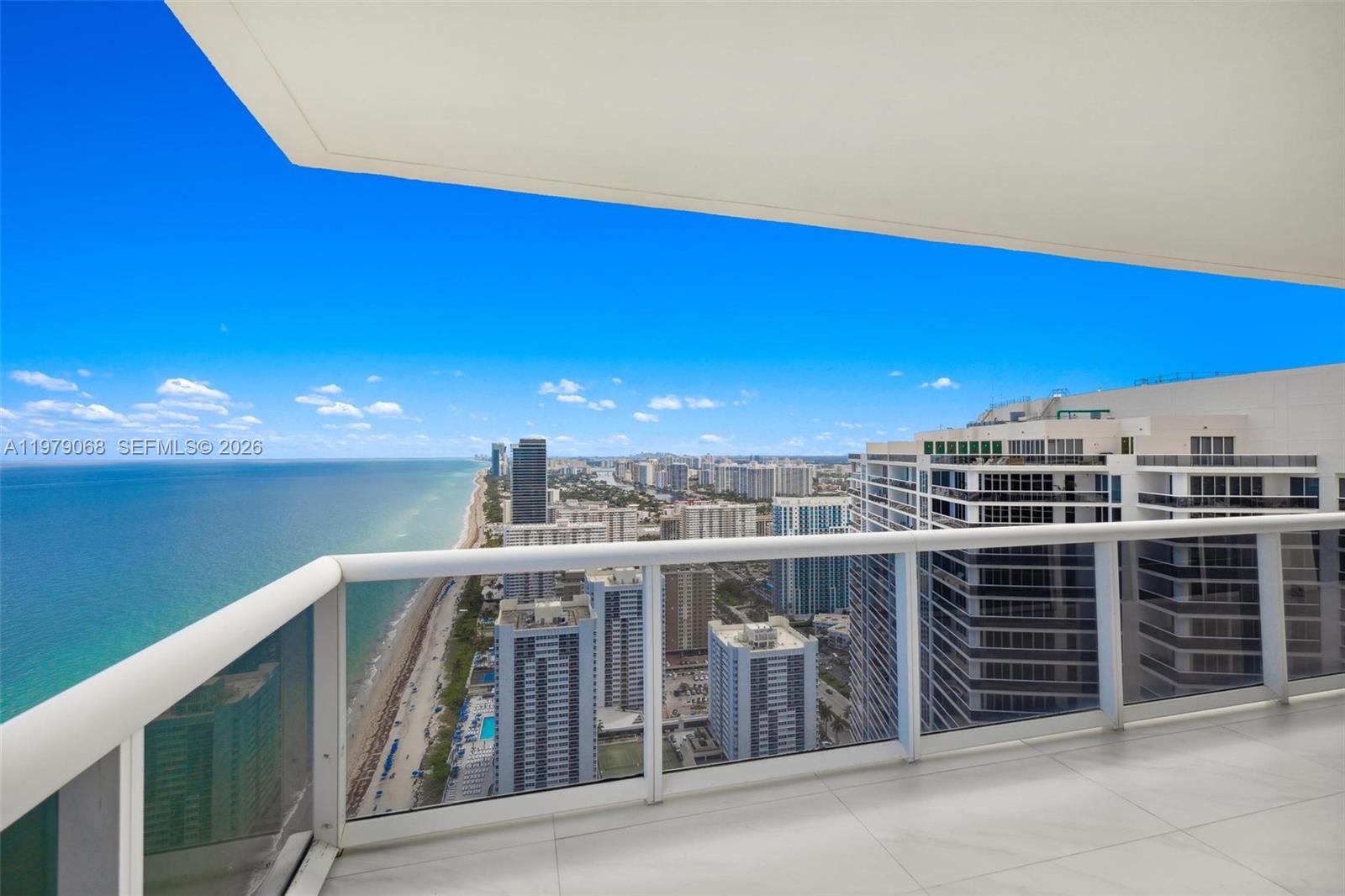 A high-rise balcony with a glass railing overlooks the ocean and a coastal city skyline — 1830 S Ocean Dr # 4502, Hallandale Beach FL 33009, HALLANDALE BEACH, FL