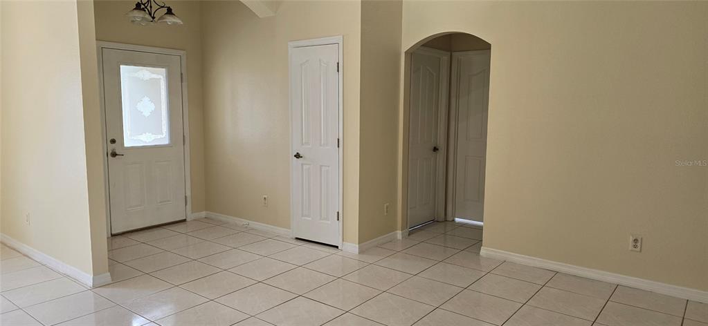 An entryway with white tile floors, a front door, and several interior doors — 15209 SW 46 CIRCLE, OCALA, FL