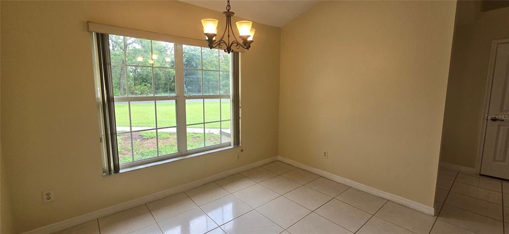 A dining area features tile flooring, a chandelier, and a large window overlooking a lawn — 15209 SW 46 CIRCLE, OCALA, FL