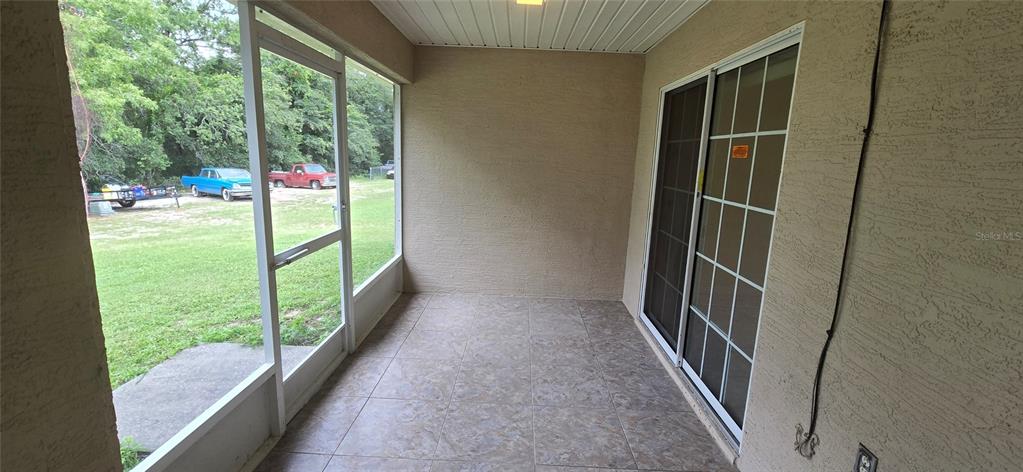 A covered, tiled patio features a screen enclosure and sliding glass doors leading indoors — 15209 SW 46 CIRCLE, OCALA, FL