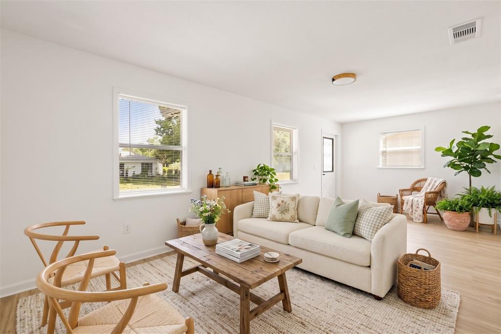 A bright living room features a cream sofa, wood coffee table, and two wooden chairs — 2312 SW FORT KING STREET, OCALA, FL