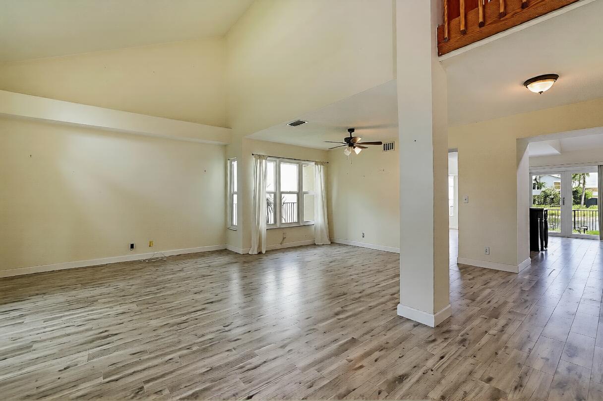 An open-concept living area features vaulted ceilings, light wood-look flooring, and a ceiling fan — 3570 Woods Walk Boulevard, Lake Worth FL 33467, LAKE WORTH, FL