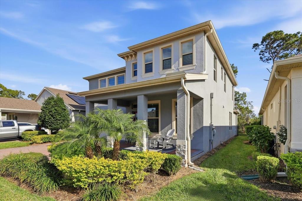 A two-story house with a covered front porch, stucco siding, and a landscaped front yard — 9611 LOST CREEK DRIVE, WINTER GARDEN, FL