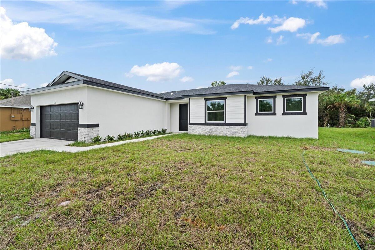 A single-story house with white stucco walls, a dark garage door, and a dark roof — 5968 Birch Drive, Fort Pierce FL 34982, FORT PIERCE, FL