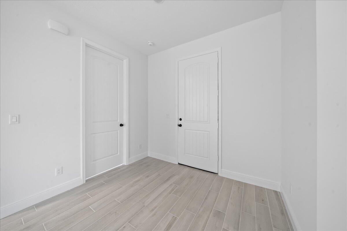 A room with white walls, light-colored wood-look tile flooring, and two white interior doors — 5968 Birch Drive, Fort Pierce FL 34982, FORT PIERCE, FL