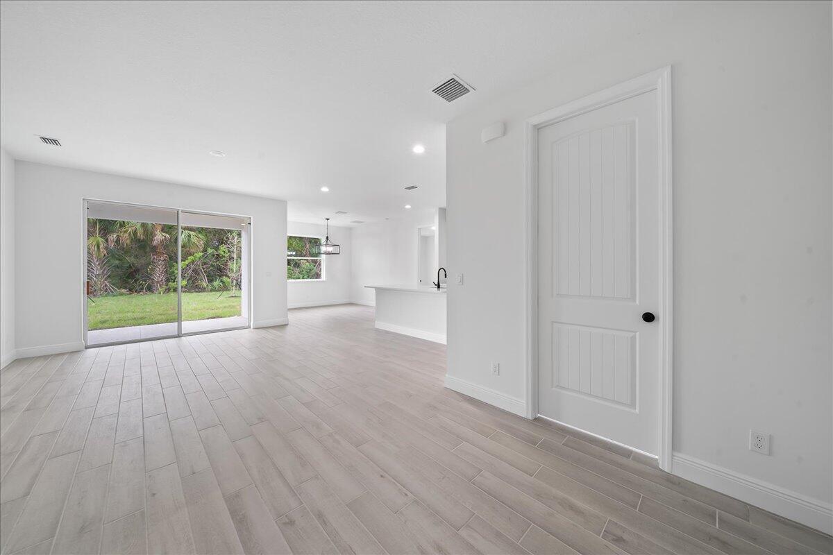 An open-concept living area features light wood-look tile flooring, white walls, and a sliding door — 5968 Birch Drive, Fort Pierce FL 34982, FORT PIERCE, FL