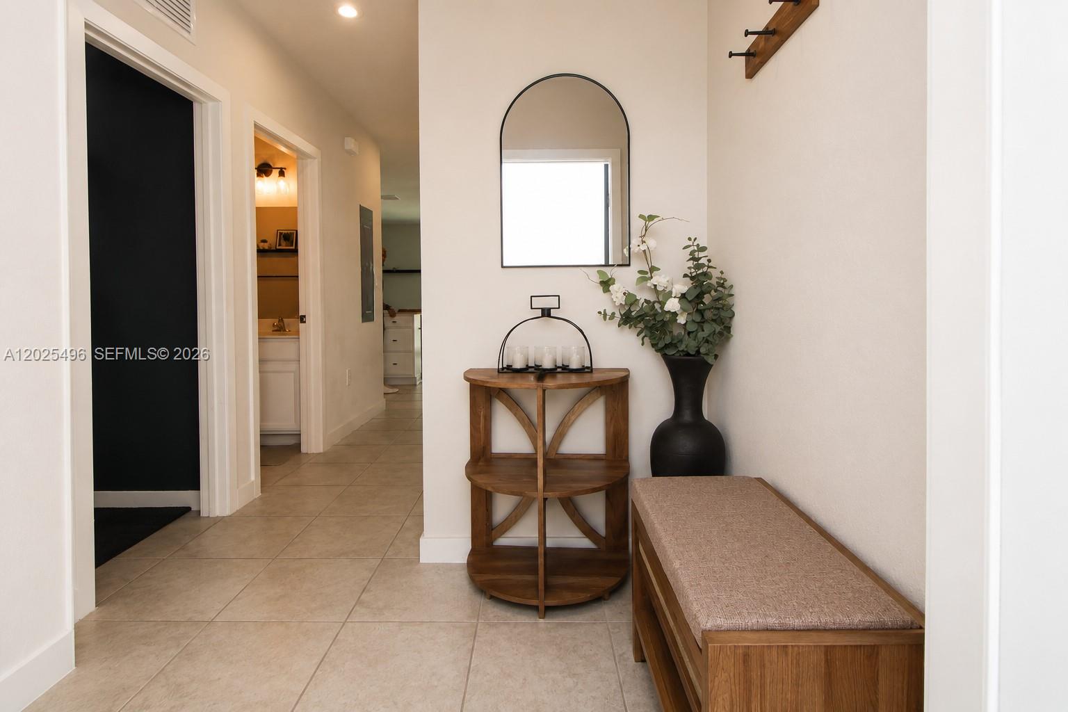 A bright entryway features a wooden corner shelf, a bench, and a wall-mounted mirror — 1009 NW 4th Ter, Florida City FL 33034, FLORIDA CITY, FL