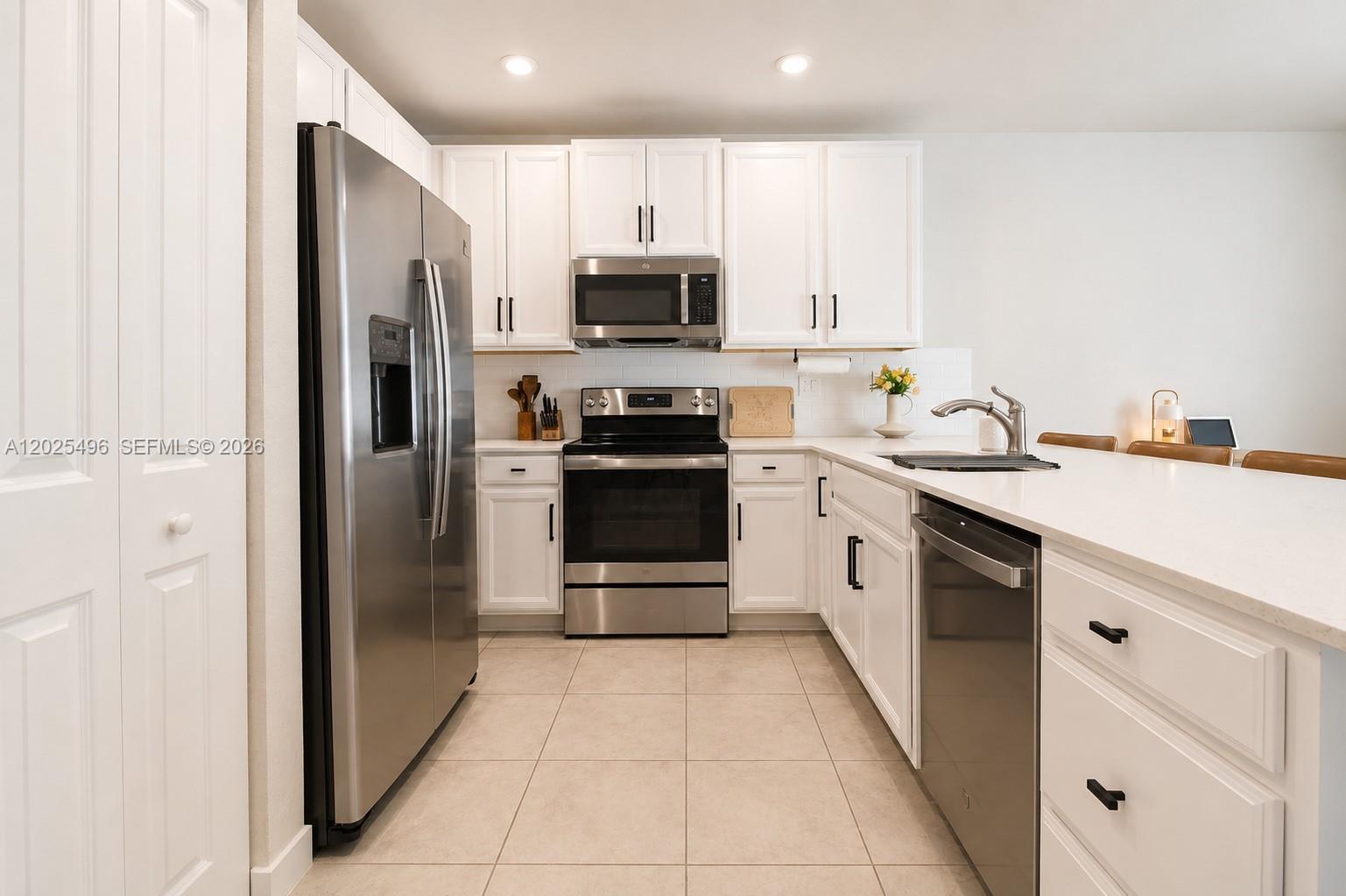 A kitchen features white cabinets, stainless steel appliances, and a white countertop island — 1009 NW 4th Ter, Florida City FL 33034, FLORIDA CITY, FL