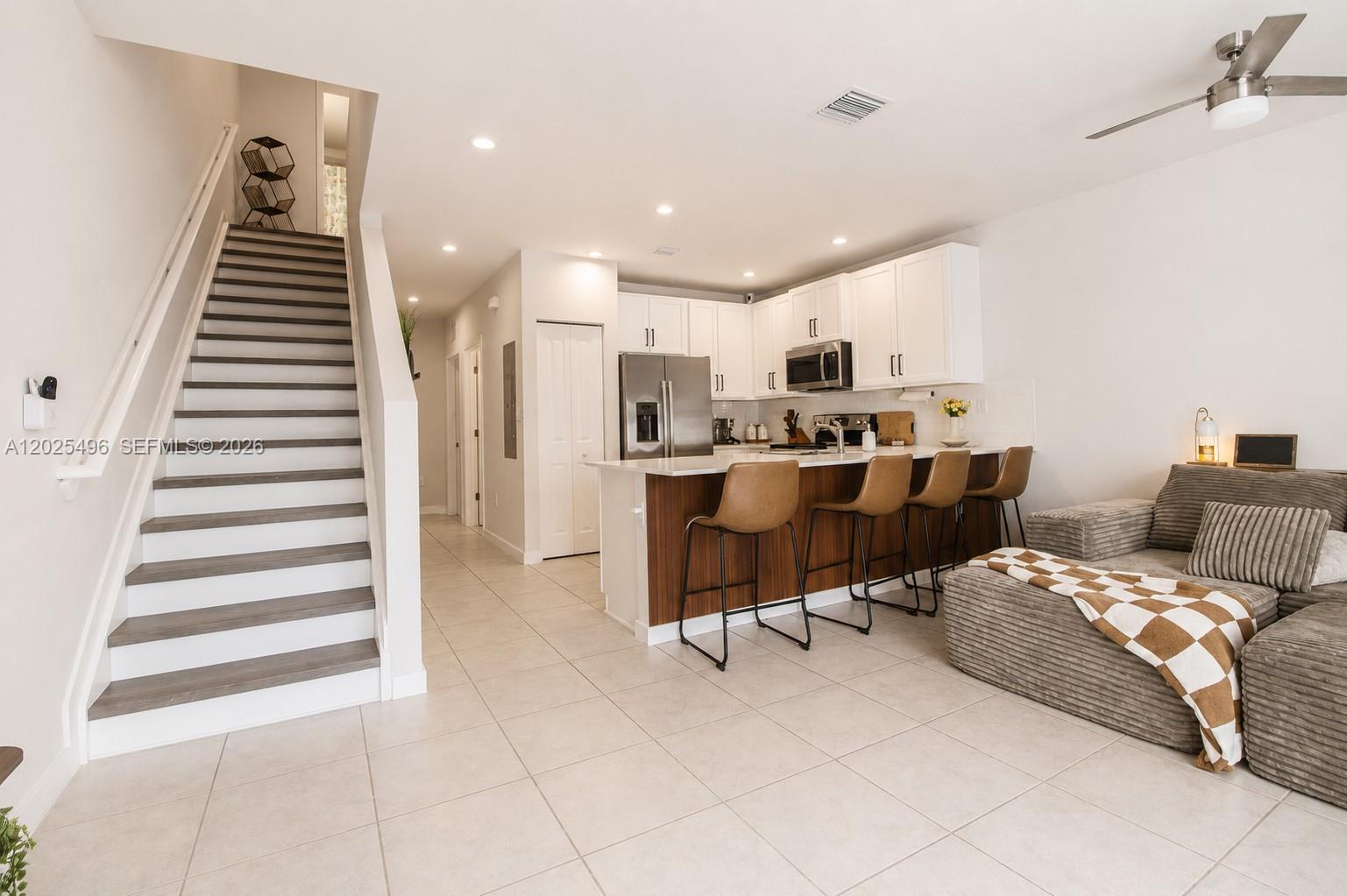 A modern kitchen with white cabinets and a breakfast bar overlooks a living area — 1009 NW 4th Ter, Florida City FL 33034, FLORIDA CITY, FL