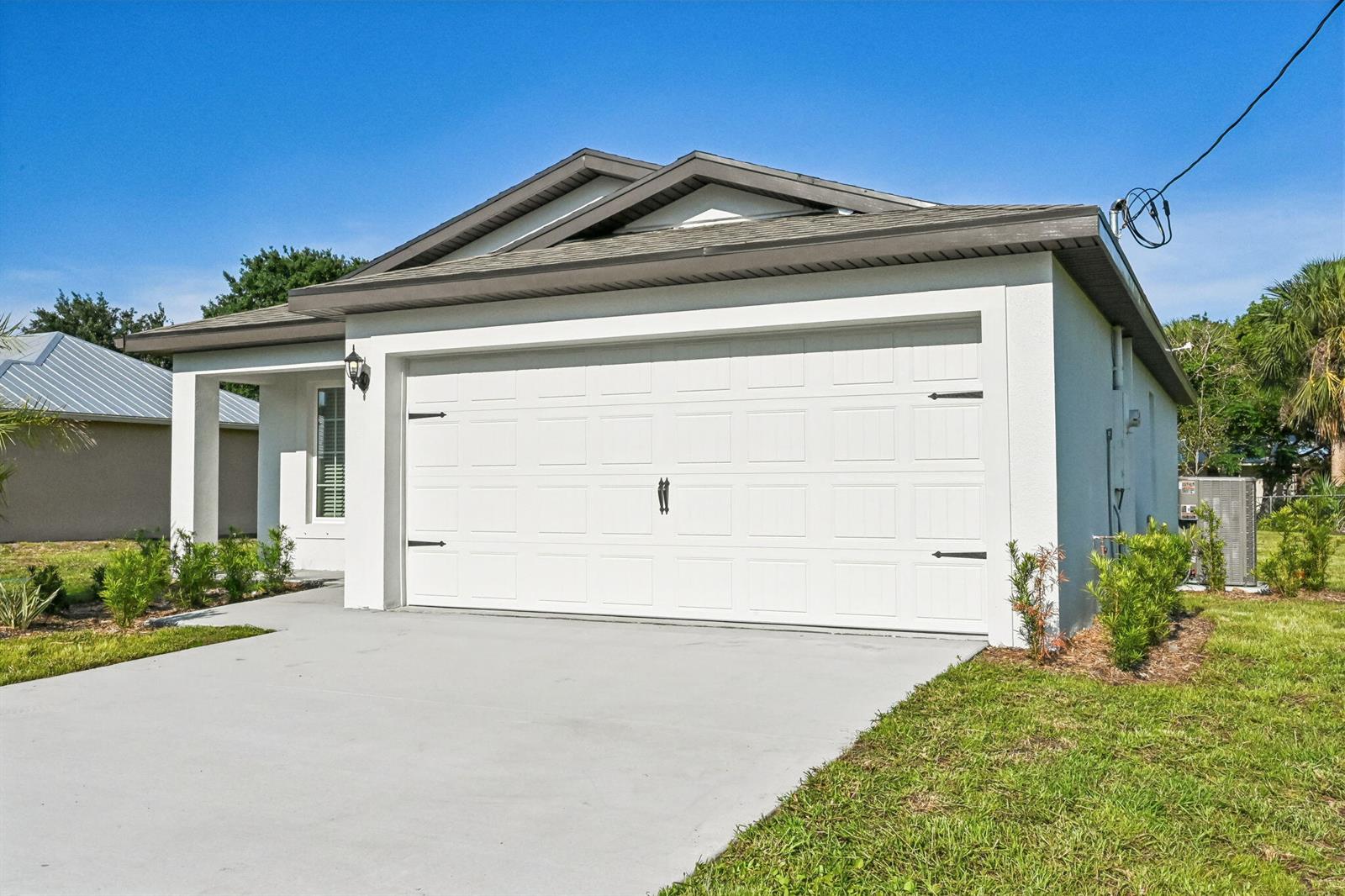 A white single-story house with a two-car garage and a concrete driveway — 5606 Seagrape Drive, Fort Pierce FL 34982, FORT PIERCE, FL