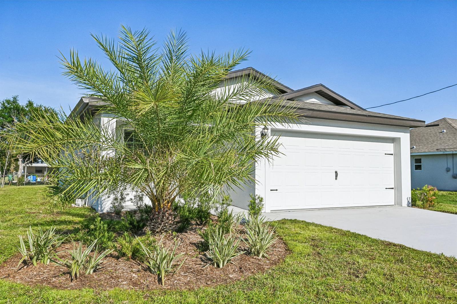 A single-story house with a white exterior, a two-car garage, and a palm tree landscaping — 5606 Seagrape Drive, Fort Pierce FL 34982, FORT PIERCE, FL