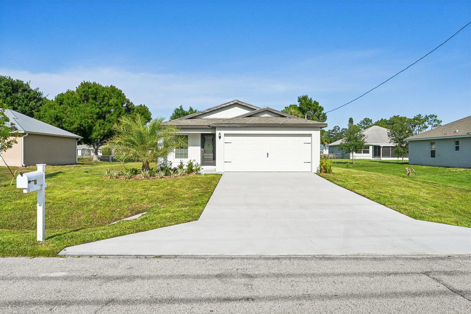 A single-story house with a white exterior, a two-car garage, and a concrete driveway — 5606 Seagrape Drive, Fort Pierce FL 34982, FORT PIERCE, FL