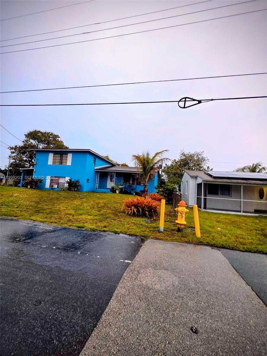 A bright blue two-story house sits on a grassy lot next to a fire hydrant — 720 SW 7th Ter, Hallandale Beach FL 33009, HALLANDALE BEACH, FL