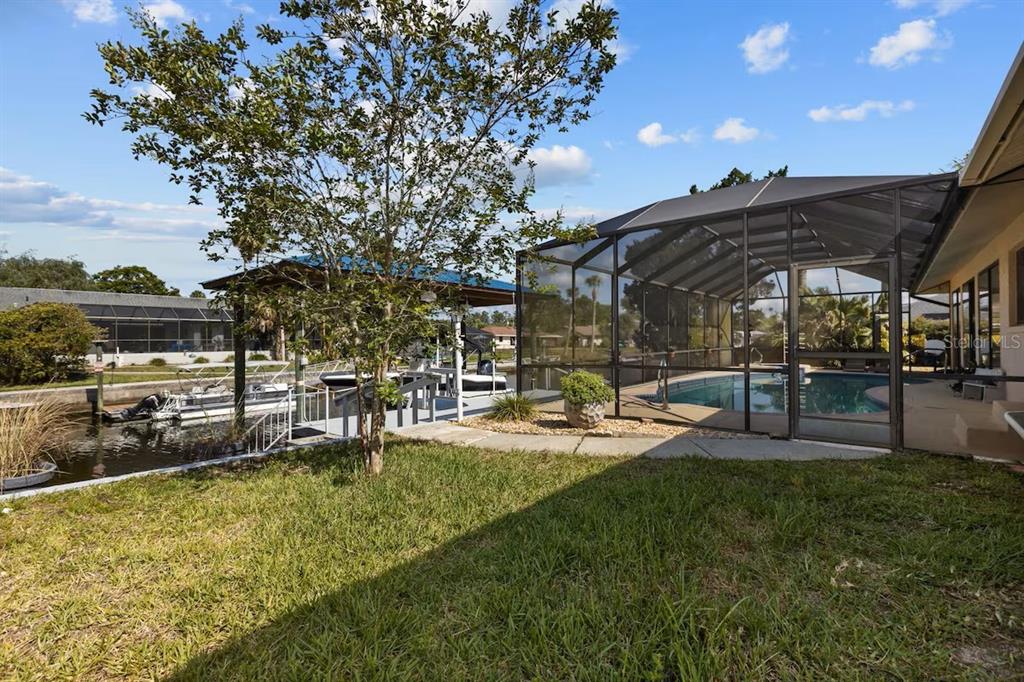A backyard view featuring a screened-in pool, a boat dock, and a canal — 3945 N TIMUCUA POINT, CRYSTAL RIVER, FL