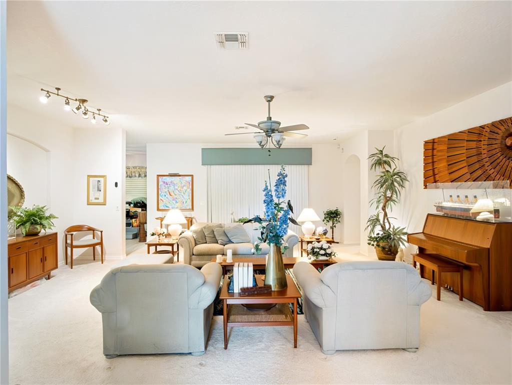 A living room features light-colored carpet, two armchairs, a sofa, and an upright piano — 4122 KINGSLEY STREET, CLERMONT, FL