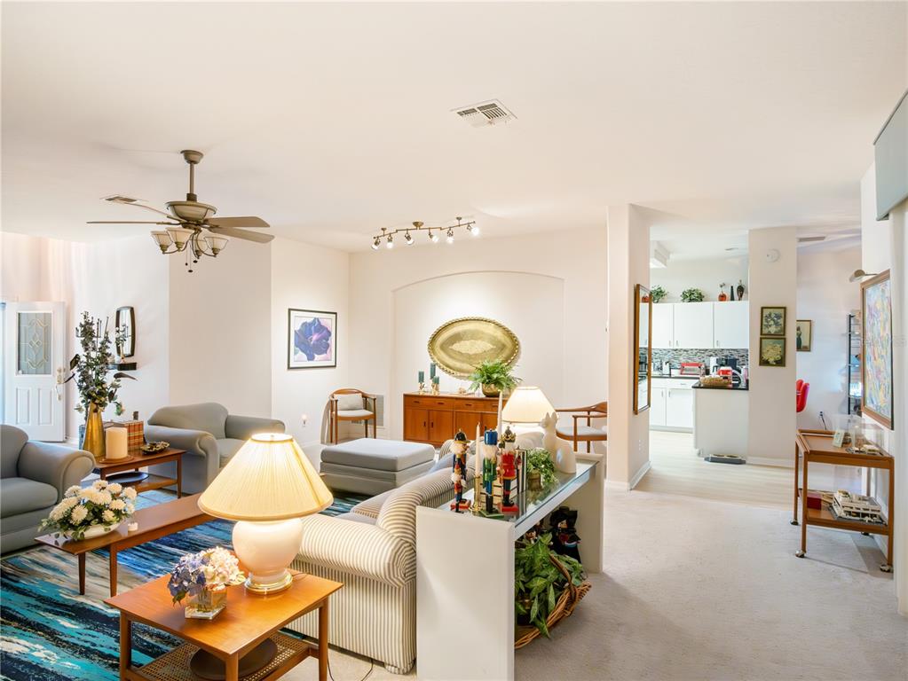 A living room features a striped sofa, blue area rug, and an open kitchen beyond — 4122 KINGSLEY STREET, CLERMONT, FL