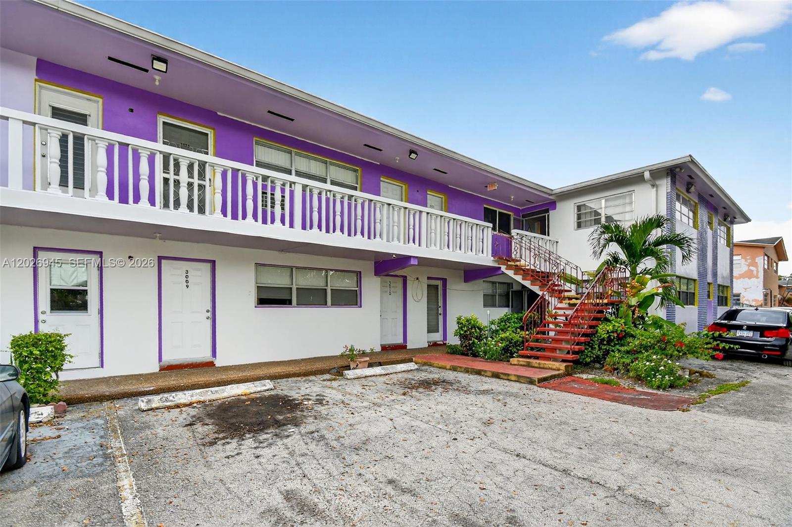 A two-story apartment building with purple accents, a white balcony, and an outdoor staircase — 245 NE 191st St # 3022, Miami FL 33179, MIAMI, FL
