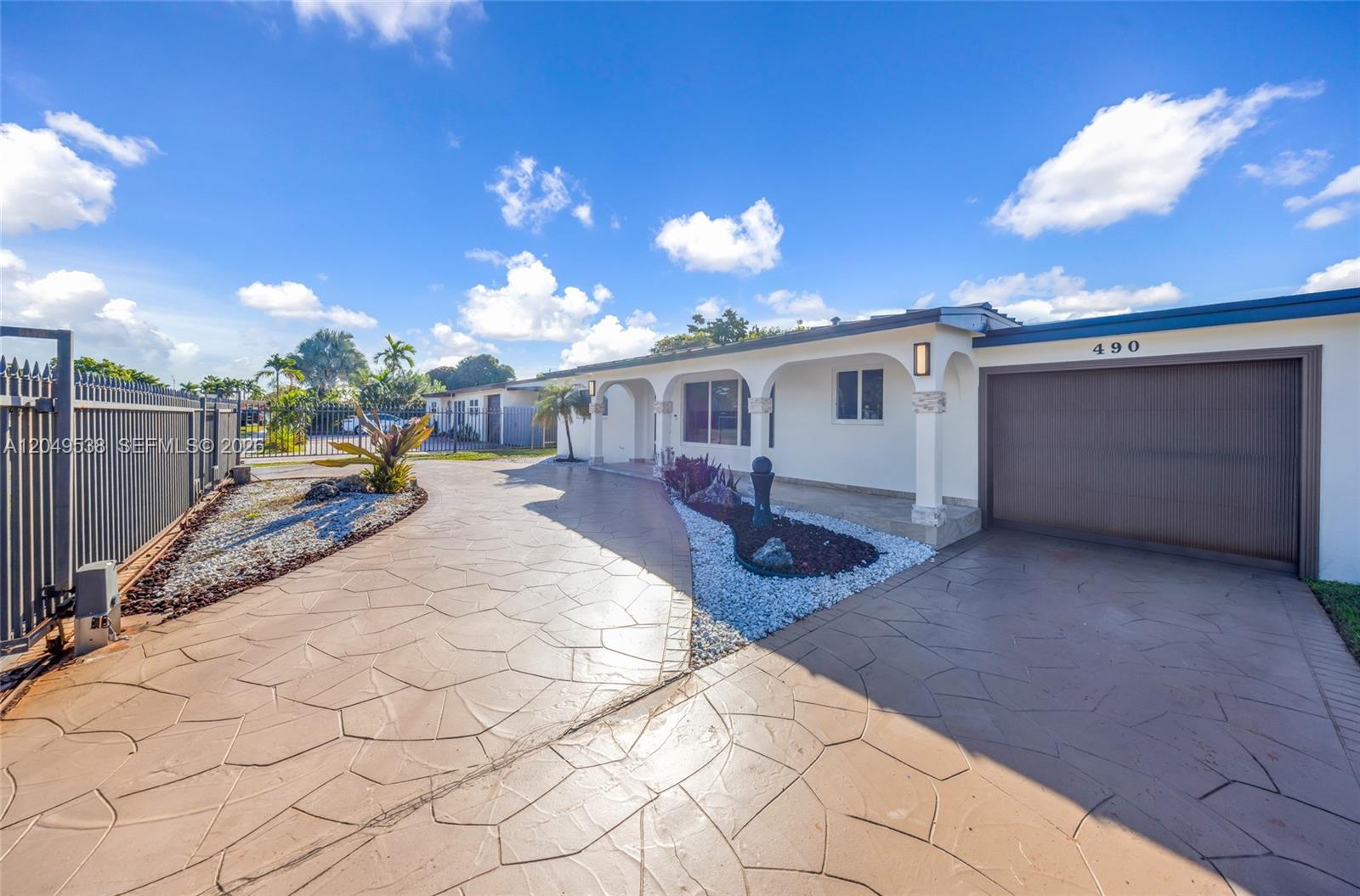 A single-story house features a stamped concrete driveway, a garage, and a covered front porch — 490 W 33rd Pl, Hialeah FL 33012, HIALEAH, FL