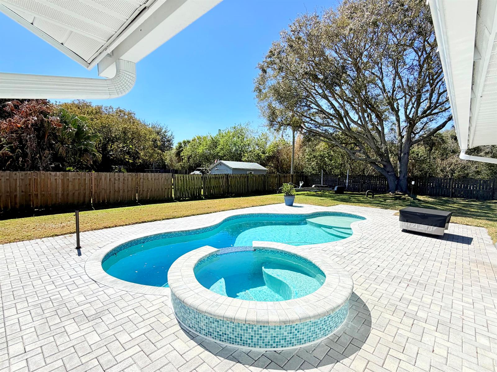 A backyard features a swimming pool with an attached hot tub and a paver patio — 311 Anchor Way, FL 34946, FL