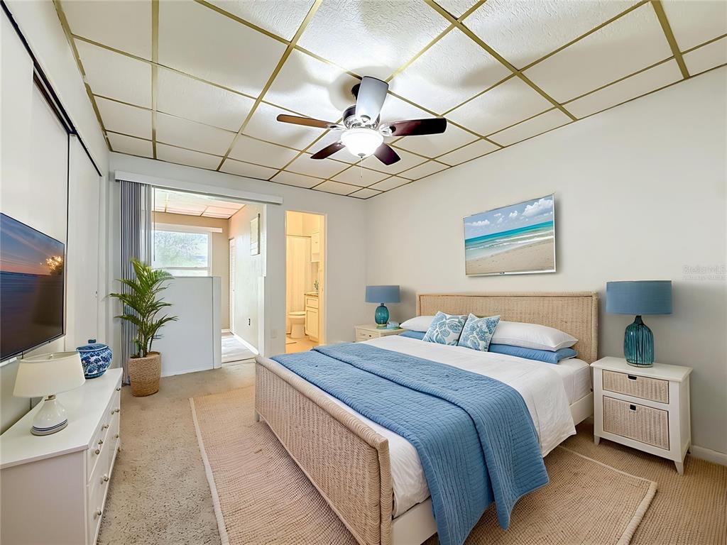 A bedroom features a bed with blue bedding, a ceiling fan, and a grid-patterned ceiling — 5860 43RD TERRACE N UNIT 1513, KENNETH CITY, FL