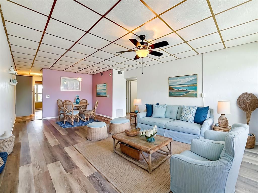 A living and dining room with a grid-patterned ceiling, light wood floors, and blue furniture — 5860 43RD TERRACE N UNIT 1513, KENNETH CITY, FL