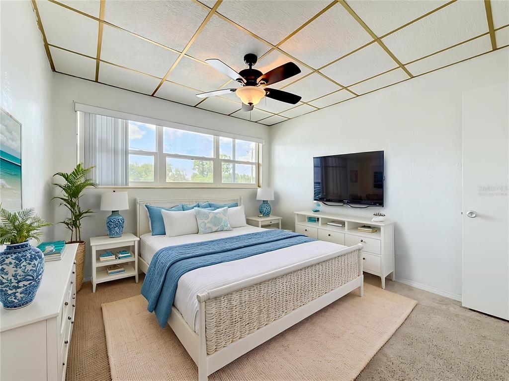 A bedroom features a white wicker bed, blue bedding, and a gold-grid drop ceiling — 5860 43RD TERRACE N UNIT 1513, KENNETH CITY, FL