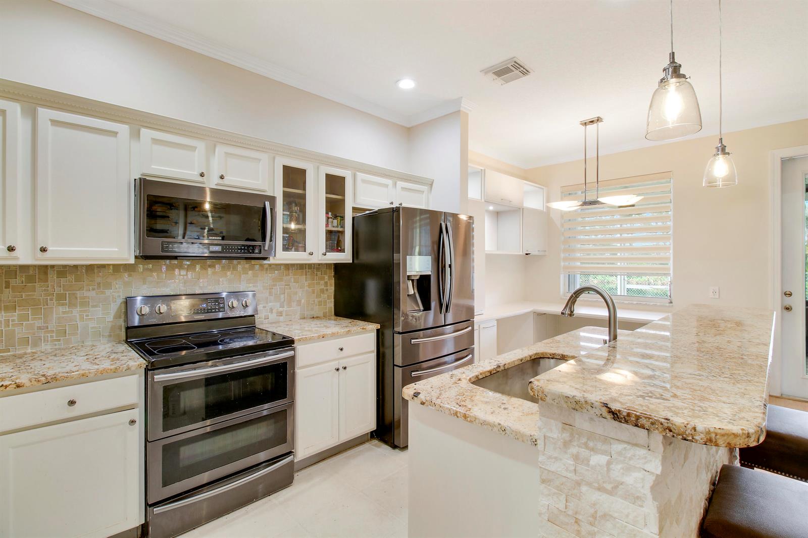 A kitchen with white cabinets, granite countertops, stainless steel appliances, and a breakfast bar — 1448 Artimino Lane, Boynton Beach FL 33436, BOYNTON BEACH, FL