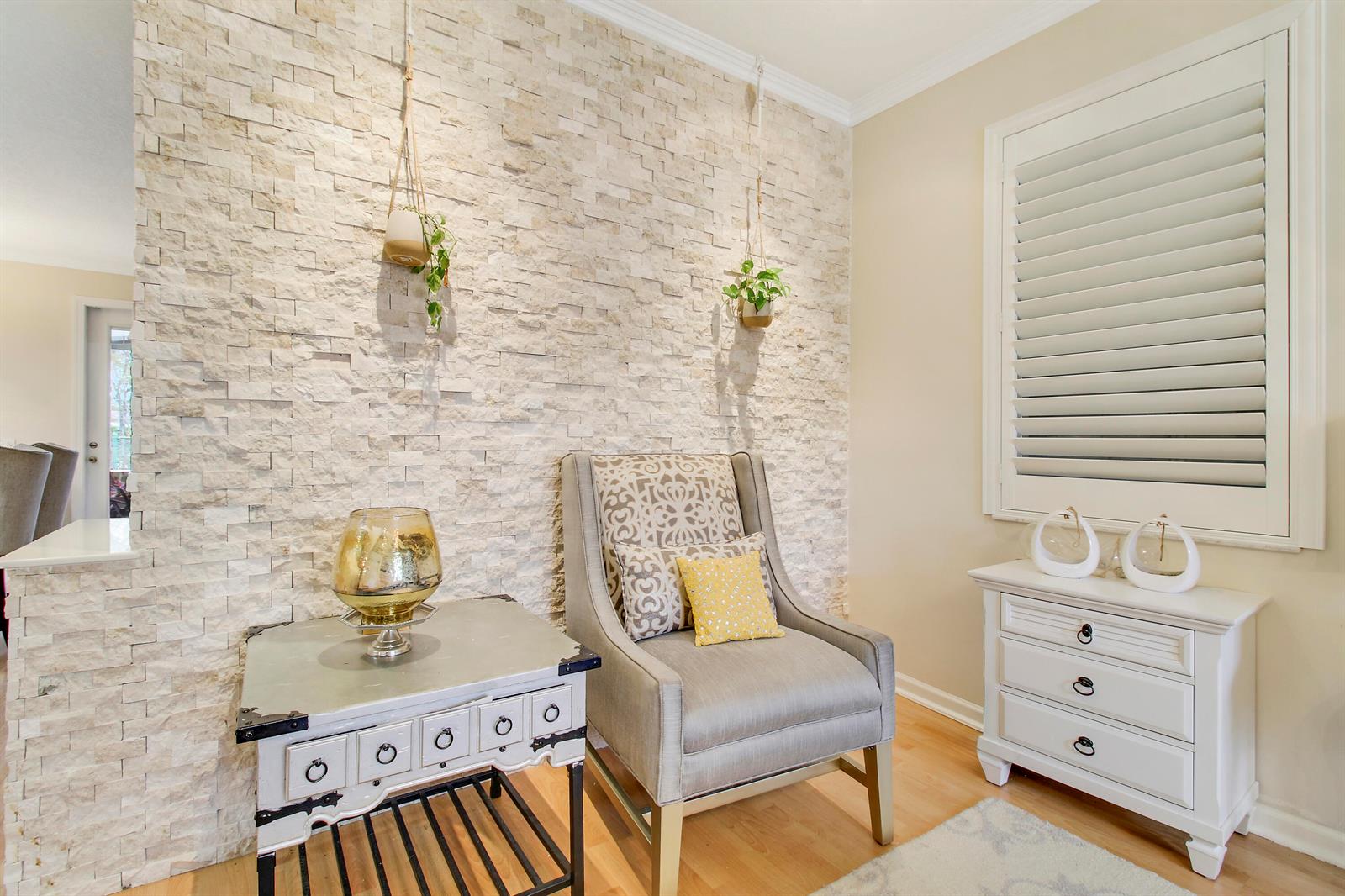 A room features a textured stone accent wall, a gray armchair, and two white cabinets — 1448 Artimino Lane, Boynton Beach FL 33436, BOYNTON BEACH, FL